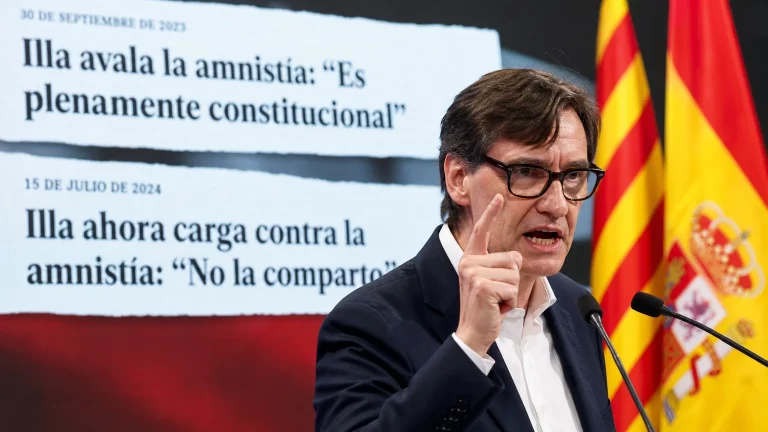 Salvador Illa gesticulando en un mitin, con una pantalla de fondo que muestra titulares contradictorios sobre la amnistía, simbolizando su cambio de postura.