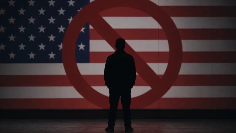 Silueta de un hombre ante una barrera, con la bandera de Estados Unidos de fondo, simbolizando la denegación de entrada.