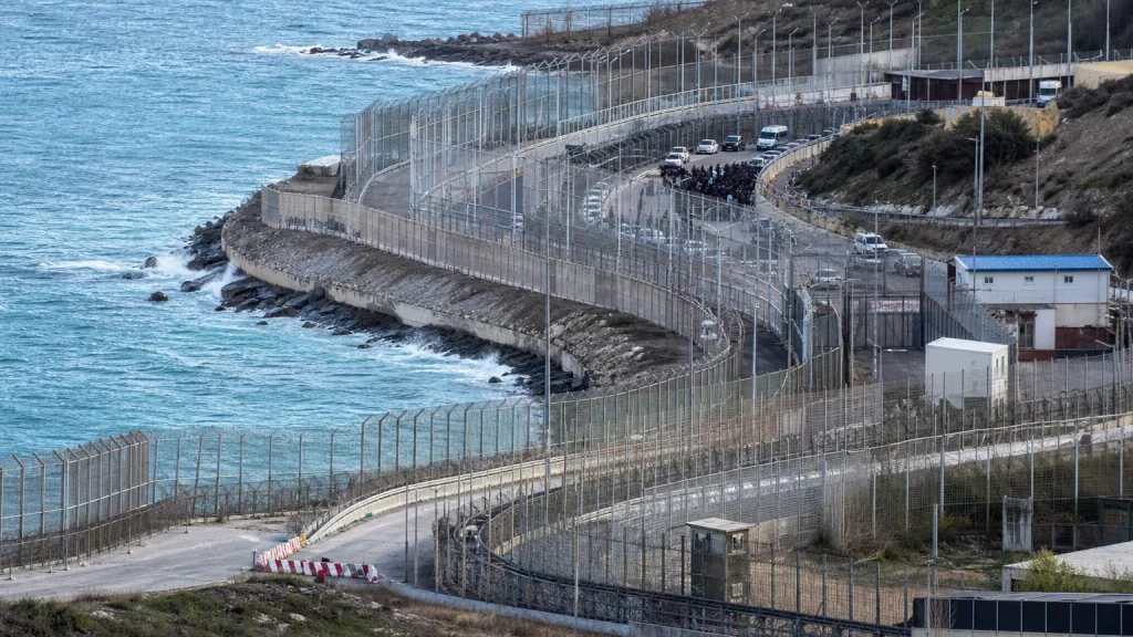 Silueta de una figura militar de alto rango de espaldas mirando un gran mapa de España con Ceuta y Melilla resaltadas, en un entorno de oficina sobrio y profesional que sugiere seguridad nacional.