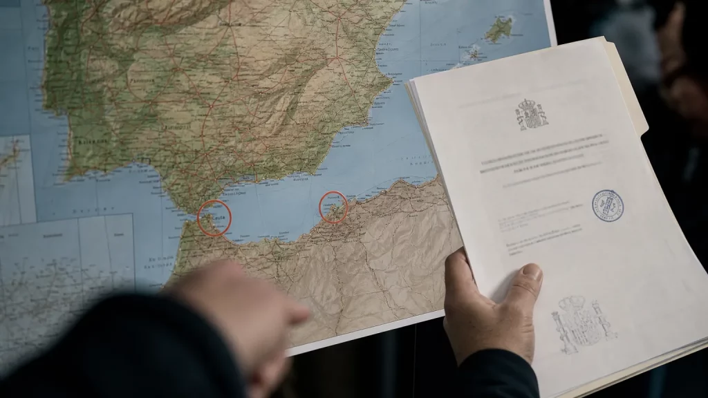 Un mapa político de España y el norte de África, con Ceuta y Melilla claramente marcadas como territorio español, y una silueta de una corona real superpuesta, simbolizando la prohibición de visita.