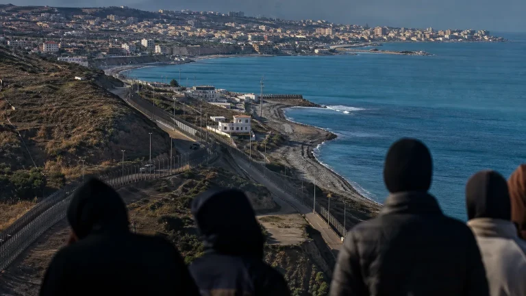 Soldado español de espaldas vigilando la frontera de Ceuta o Melilla con el mar de fondo, simbolizando la defensa de la soberanía.