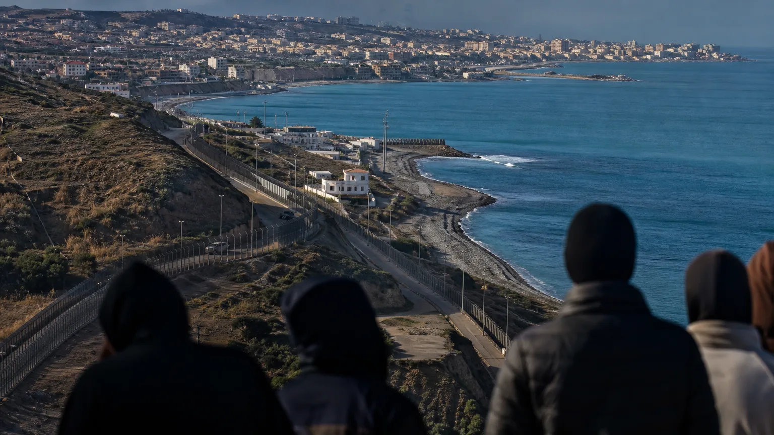 Soldado español de espaldas vigilando la frontera de Ceuta o Melilla con el mar de fondo, simbolizando la defensa de la soberanía.