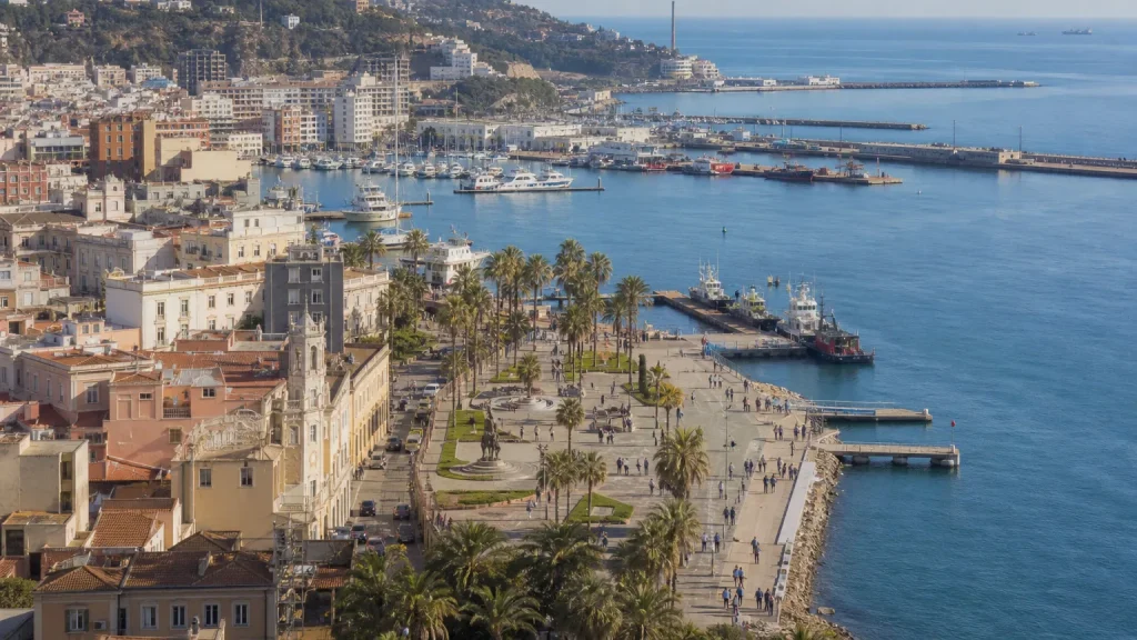 Vista panorámica de una ciudad costera española, como Ceuta o Melilla, con personas paseando en la distancia, simbolizando la vida cotidiana y la soberanía frente a decisiones políticas lejanas.